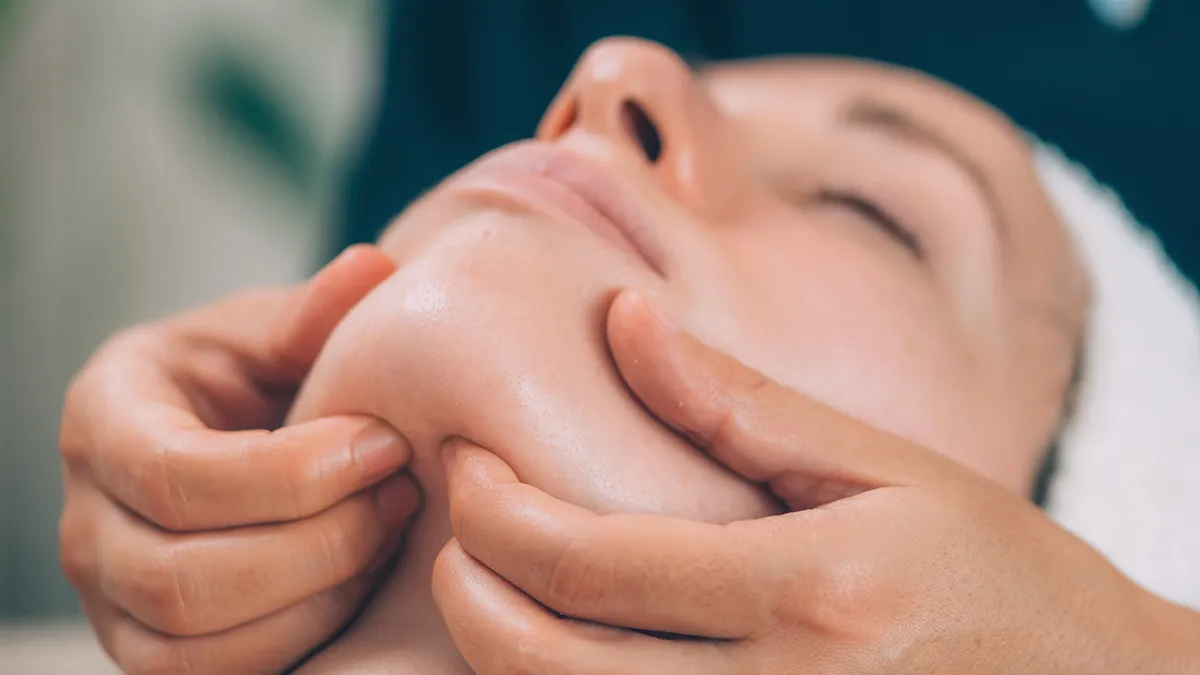 A woman getting lymphatic drainage massage on face, under the chin area